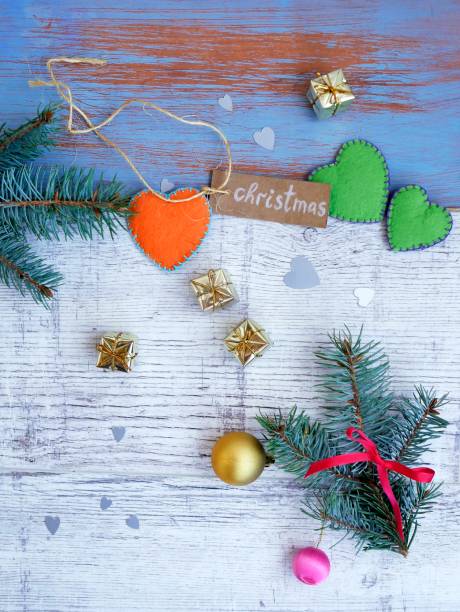 Christmas, white and blue wooden background, spruce branches, small gold gifts and handmade hearts