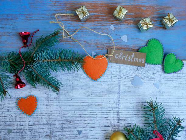 Christmas, white and blue wooden background, spruce branches, small gold gifts and handmade hearts