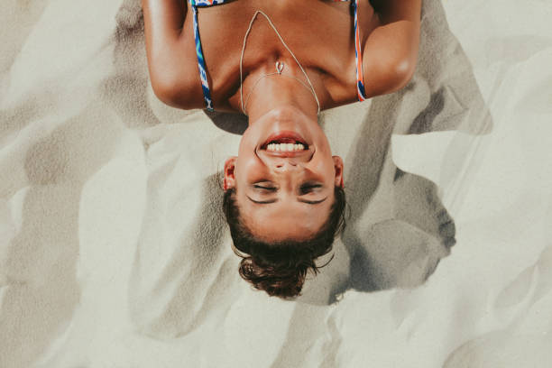 primer plano de mujer relax sobre la arena de la playa - tomando el sol fotografías e imágenes de stock