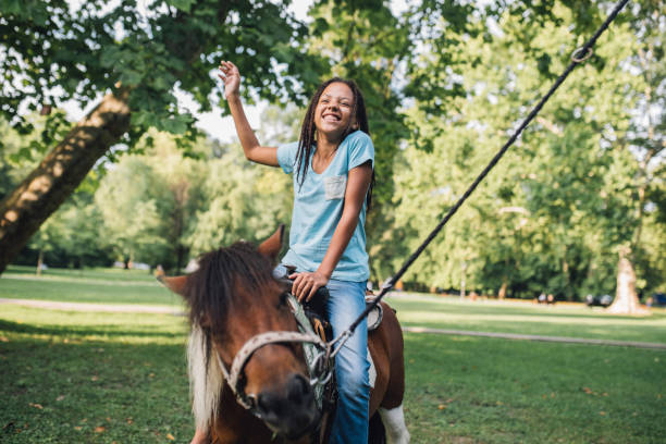 adolescente che agita la mano mentre cavalca un pony - horse child pony little girls foto e immagini stock