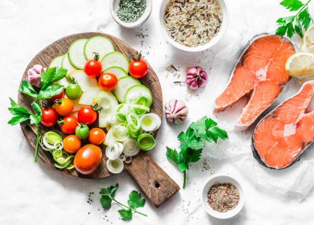istock Ingredients for  healthy, balanced lunch - salmon and vegetables. Red fish, zucchini, squash, cherry tomatoes, leek, wild rice, spices on a light background, top view. Flat lay 1020682046