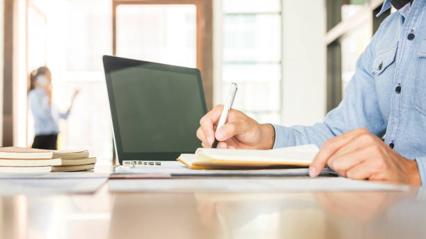 istock Midsection Of Businessman Writing On Book While Working In Office 1020682248