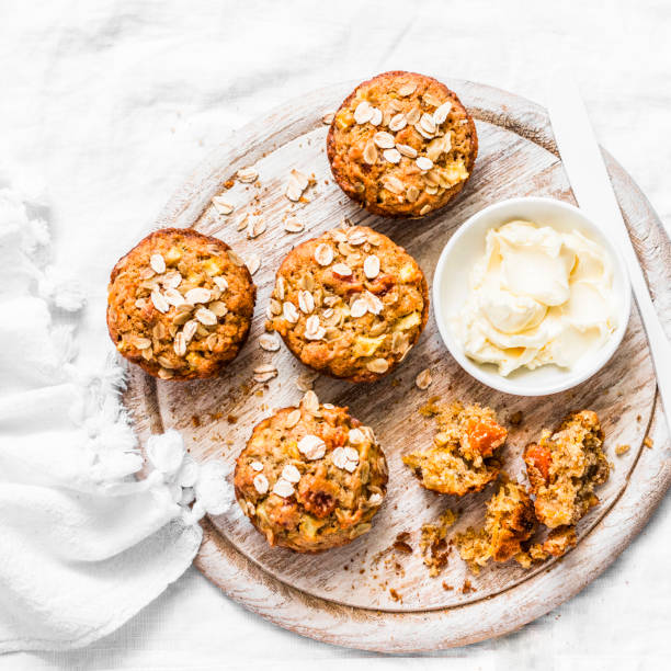 ziarniste płatki owsiane bezglutenowe babeczki na rustykalnym pokładzie do krojenia na jasnym tle. płaski lay - muffin zdjęcia i obrazy z banku zdjęć