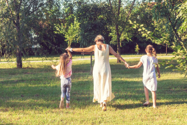 istock Playful mother and daughters walking in the park. 1020686616
