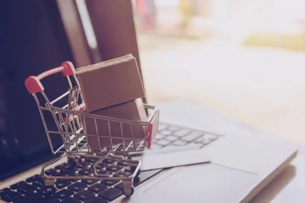 Shopping online concept - Shopping service on The online web. with payment by credit card and offers home delivery. parcel or Paper cartons with a shopping cart on a laptop keyboard