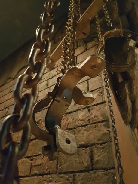 Restraints of imprisonment leg cuffs and chains hanging from wall in cell.