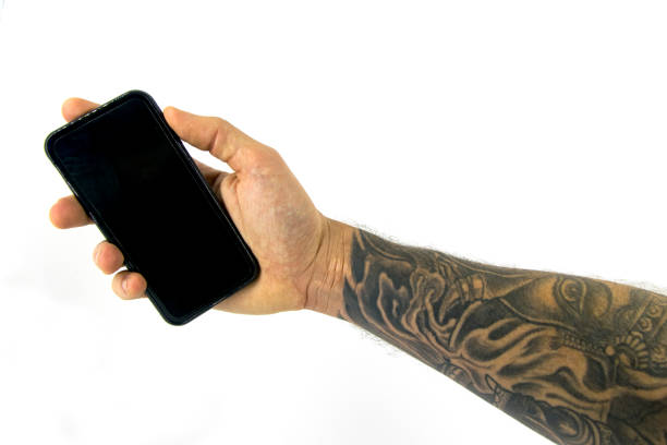 Caucasian hand with tattooed fore arm holding phone isolated in white background
