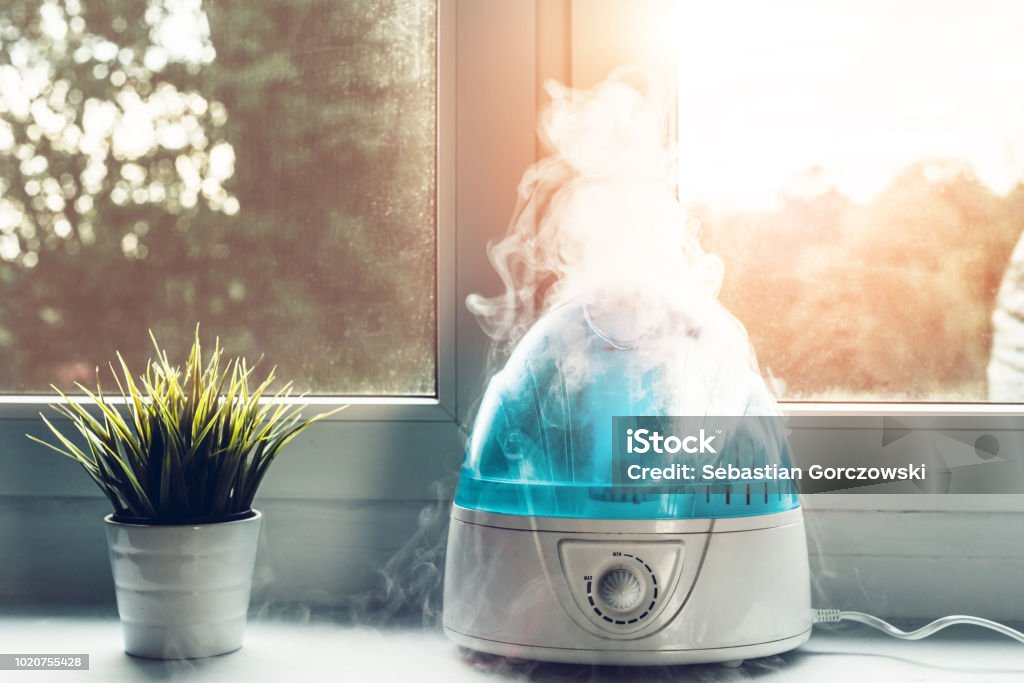 Air humidifier during work. The white humidifier moistens dry air. Improving the comfort of living in the home, apartment. Improving the well-being of people. Humidifier Stock Photo