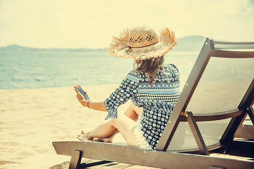 Woman with mobile in tropical beach chair