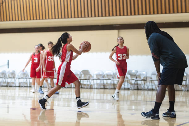 Co-ed high school basketball practice Coach has his co-ed basketball team run layup drills during practice. One girl is dribbling and about to pass to her teammate. sports court photos stock pictures, royalty-free photos & images