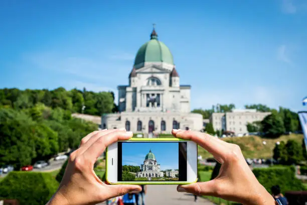 Woman taking a photo of Saint-Joseph's Oratory with her mobile phone on a sunday afternoon during summer in Montreal.