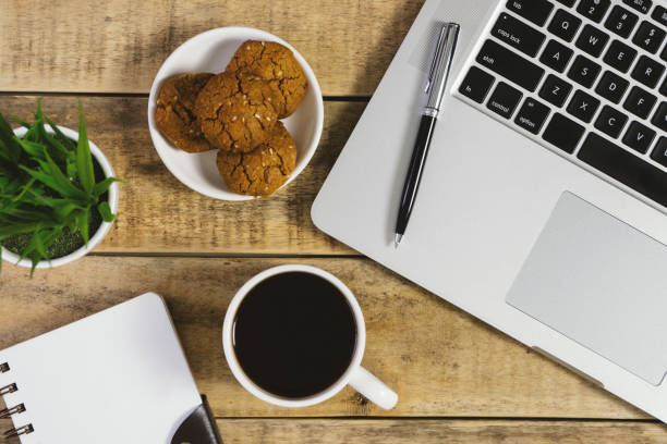 Laptop, diary and breakfast on wood background.