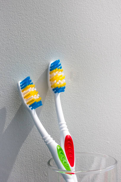 istock Two new toothbrushes in a glass on a light background 1020945150