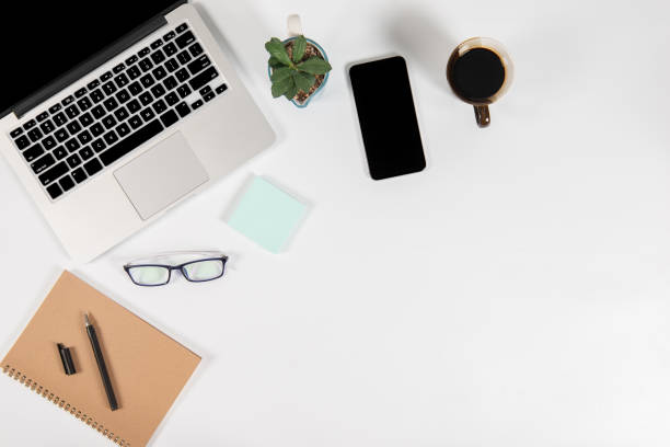 istock Office table with laptop computer, smartphone, pen, notebook and coffee on isolated pure white background / Laptop and tablet mockup concept. (Selective Focus) 1020950308
