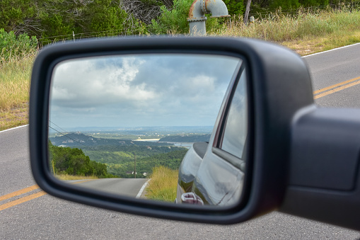 Lake and hill country on a Texas backroad outside of Austin in the rear view mirror