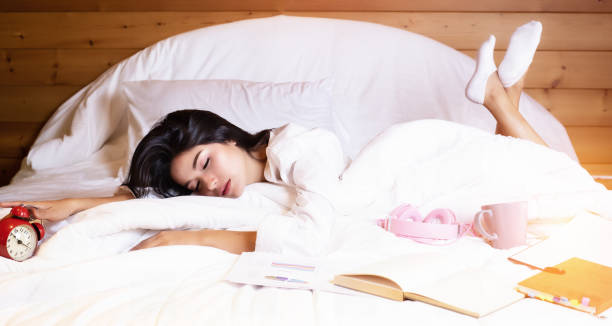 istock The beautifu laday iis sleeping on bed,beside work sheet and book,blurry light around. 1020955632