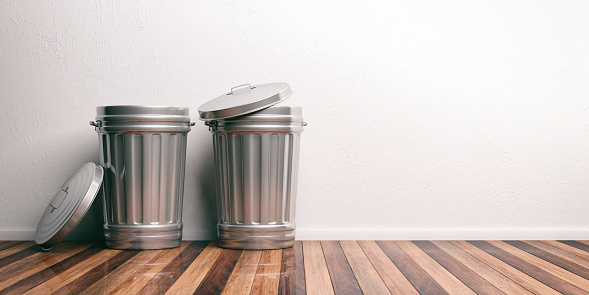Three black rubbish bins against a white wall with copy space. Stock photo