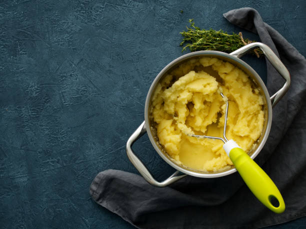 Mashed potatoes in bowl on dark stone blue table, rosemary, napkin, top view stock photo