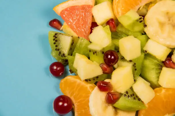 Fresh fruit salad on a blue plate with a place for the inscription. Citrus salad with copyspace