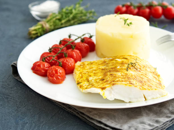 istock Fish cod baked in oven with mashed potatoes, tomatoes, diet healthy food. Dark gray background, side view 1020979202