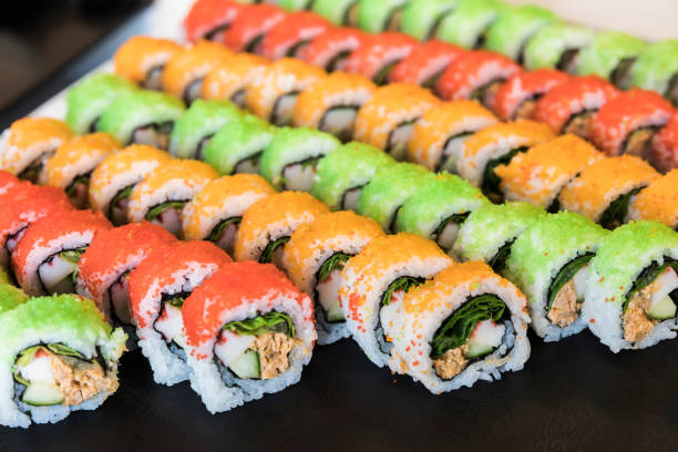 Assortment of healthy multicolored maki sushi rolls Assortment of healhy multicolored maki sushi rolls. The tasty rolls are very colorful with red, orange and green colored caviar on top, and are filled with salad, fish and crabfish. sushi plate stock pictures, royalty-free photos & images