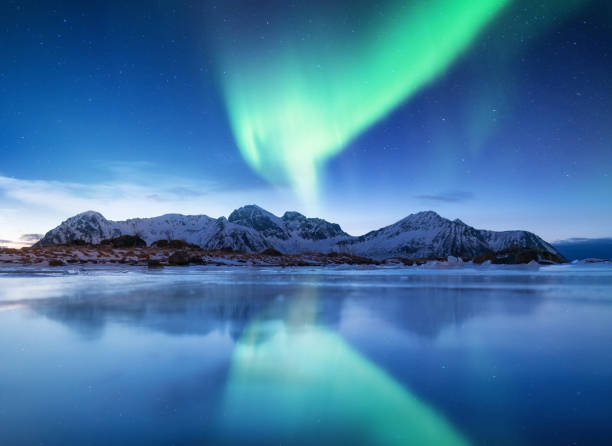 aurora boreal en las islas lofoten, noruega. aurora boreal verde. cielo nocturno con luces polares. paisaje de invierno noche con la aurora y la reflexión sobre la superficie del hielo. fondo natural en el noruega - tromso fjord winter mountain fotografías e imágenes de stock