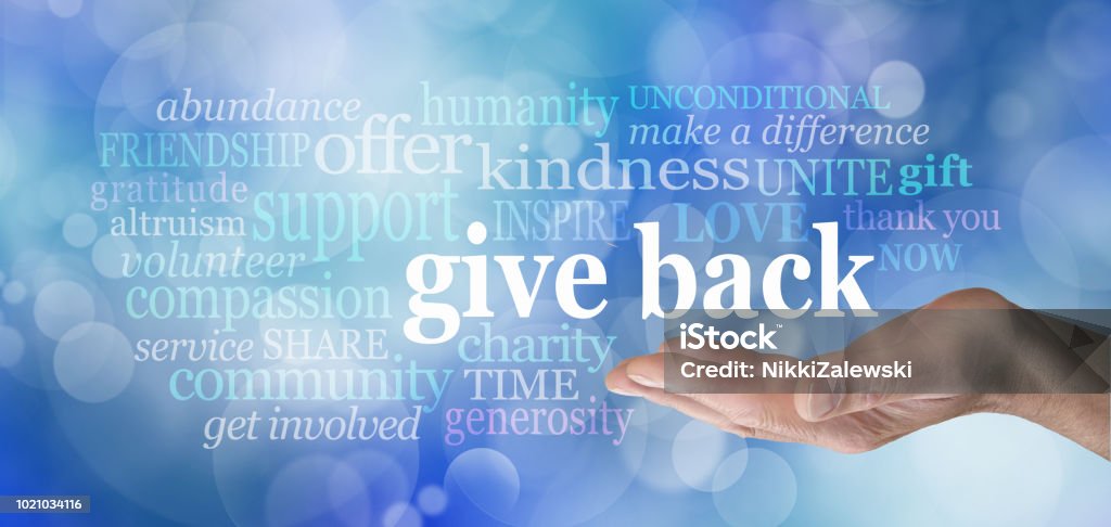 GIVE BACK word tag cloud male hand with the words GIVE BACK floating above surrounded by a word cloud against a blue bokeh background Charity and Relief Work Stock Photo