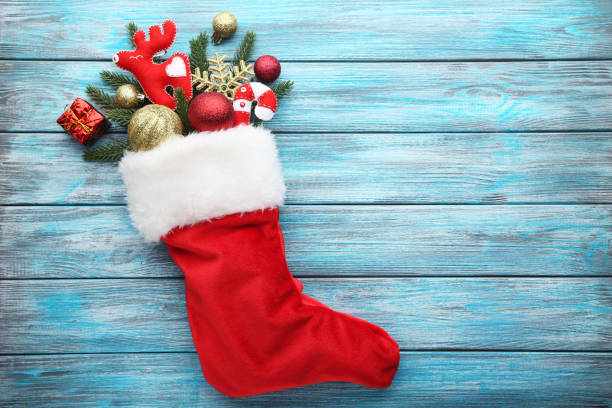 istock Red stocking with fir-tree branches and christmas decorations on wooden table 1021061770