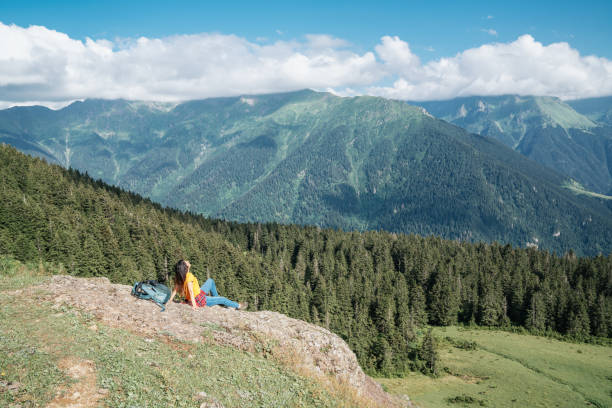 istock Young happy woman with backpack standing on a rock looking to a valley below 1021065640