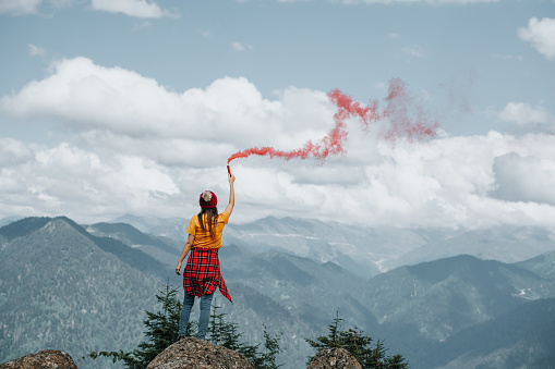 Woman on mountain peak with red flare.Inspiration conceptWoman on mountain peak with red flare.Inspiration concept