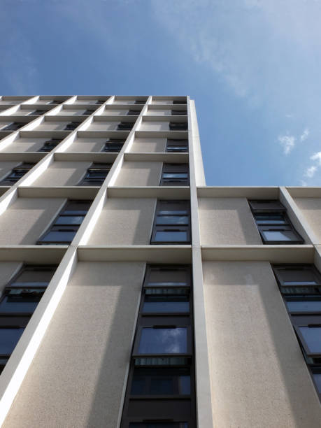 istock vertical view of a white high white modern concrete building development with blue sunny sky reflected in the windows 1021105664