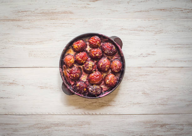Baked plum in a frying pan. Rustic style.