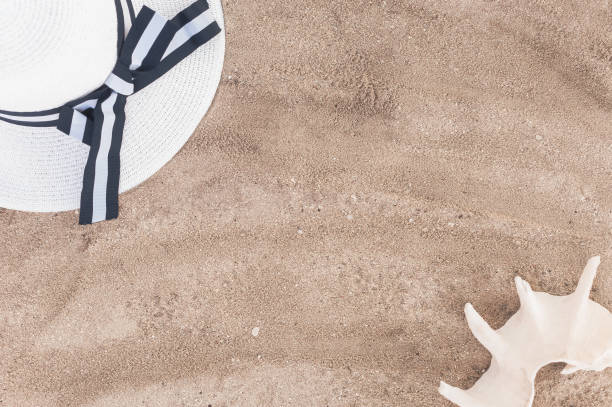 istock A white hat with wide brim and a seashell lie on the fine light sand. Background with beach accessories 1021136798