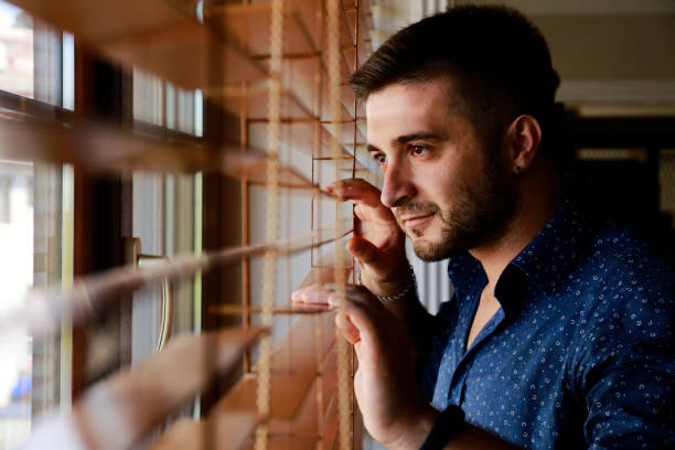 istock Man looking through a jalousie 1021147424