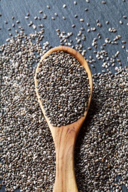 istock Chia seeds in wooden spoon on stone table top view. 1021149868