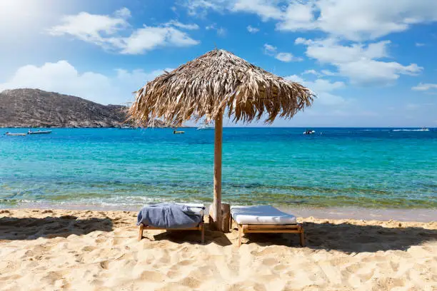 Umbrella and sunbeds in front of turqouise sea at the famous Mylopotas beach on the island of Ios, Cyclades, Greece