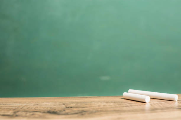 istock Chalk on wooden school desk with chalkboard. 1021174610