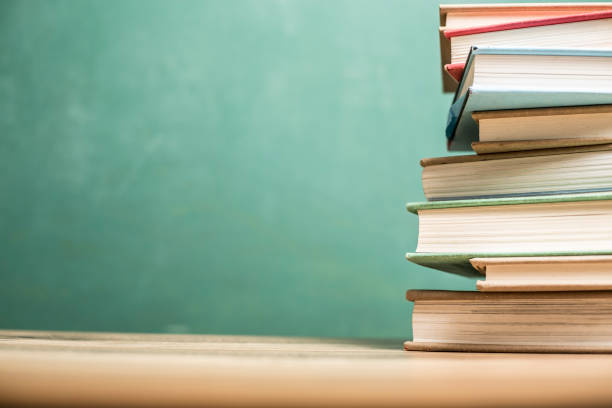 istock Textbooks on wooden school desk with chalkboard. 1021174676