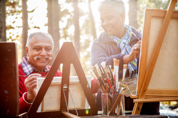active senior adult couple enjoys art hobby outdoors. - indiana autumn woods forest imagens e fotografias de stock