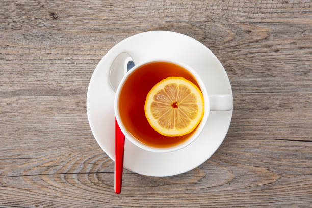 istock Tea with lemon in a white mug on a wooden table. Tea spoon. Top view. Copy space. 1021190632