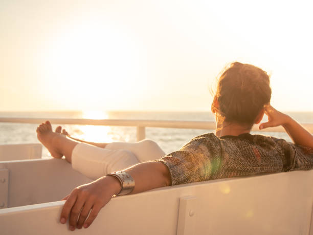 croisière bateau vacances jeune femme appréciant lever du soleil sur les voyages en mer avec les jambes et les pieds vers le haut - passenger ship flash photos et images de collection