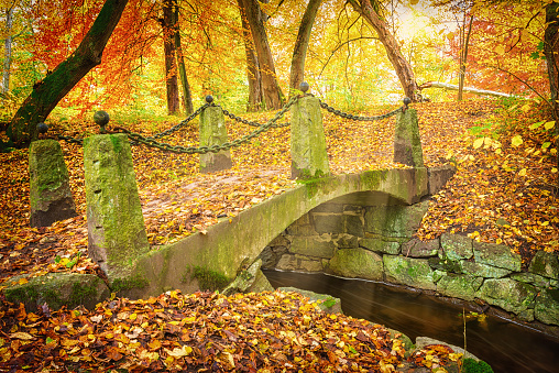 Old stone bridge over small stream. Public park in autumn Sweden.