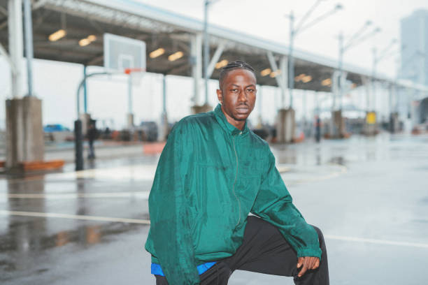 Retro image with African American guy in retro sports clothing. Images are taken with direct flash, grain is added and colors are set as color film images from 90s. \nPortrait of African American athlete, exercising on rainy day outdoors