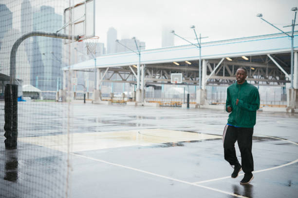 african american man jogging on rainy day - retro revival basketball american culture sport imagens e fotografias de stock