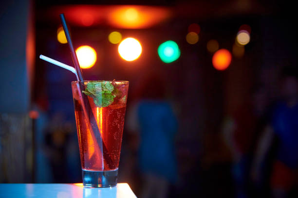 Bright cool cocktail with bubbles and straws on a dark background with bokeh.