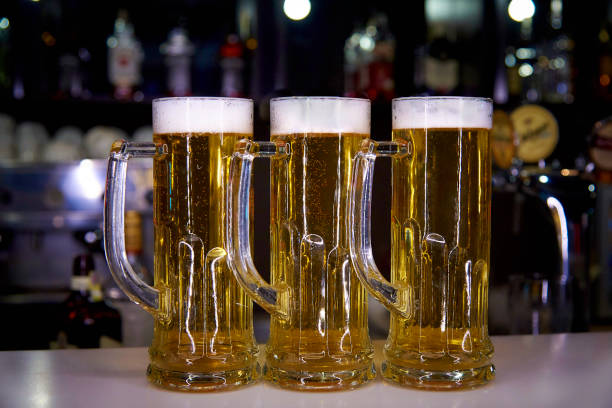 istock Three mugs with a cold beer on the background of a blurry bar. 1021221638