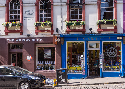 Edinburgh, Scotland, UK - June 13, 2012: The brown facade of The Whisky Shop and the blue facade of Cuttea Sark souvenir store along Victoria Street with people inside.