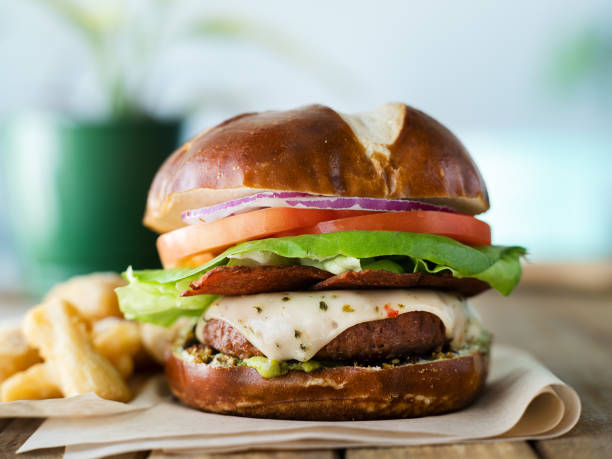 vegan cheese burger on pretzel bun and meatless bacon vegan cheese burger on pretzel bun and meatless bacon meat substitute stock pictures, royalty-free photos & images