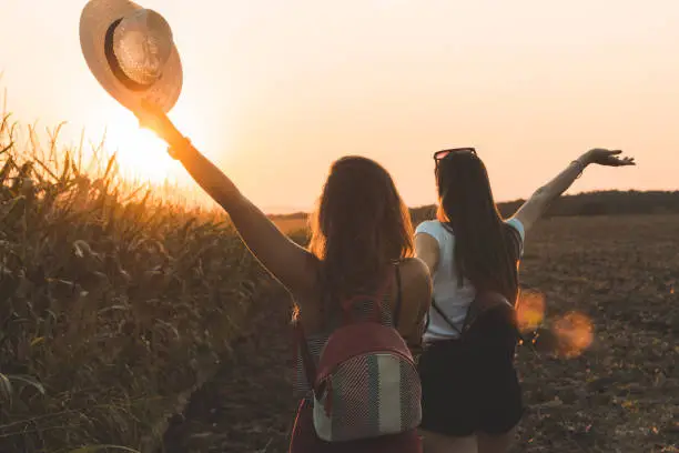 Photo of Two women having fun near the cornfield at sunset