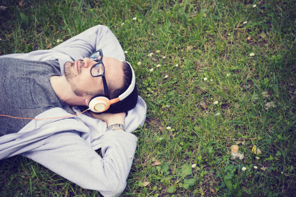istock Above view of relaxed man enjoying in music while lying on grass. 1021251680
